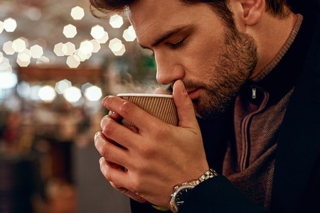 Close-up of man drinking mulled wine at the street food market.の写真素材