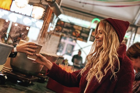 Close-up of woman buying mulled wine at the street food market.の写真素材
