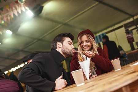 Close-up of young couple are eating churros at the street food market.の写真素材