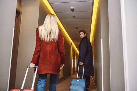 Couple of travellers in the hall. Rear view of young couple enter to the hotelの写真素材