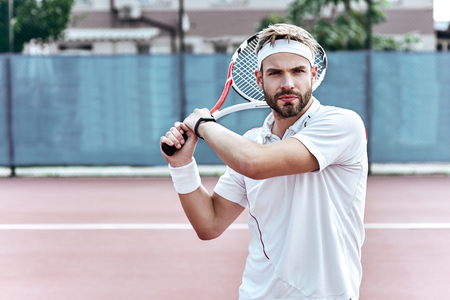 Concentration. Handsome man is playing tennisの写真素材