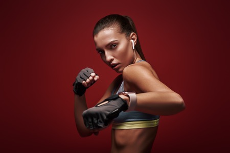 Perfect shape. Young sportswoman standing over red background is ready to exerciseの写真素材