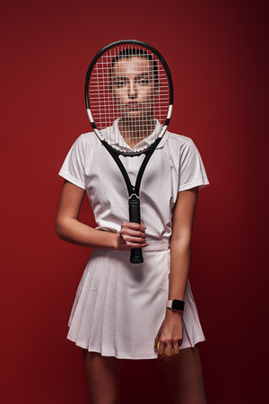 All it takes is all youâve got! Young tennis player standing isolated over red background with a racket and a ballの写真素材