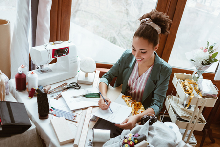 Top view of young woman tailor with not pad is drawing by pencilの写真素材