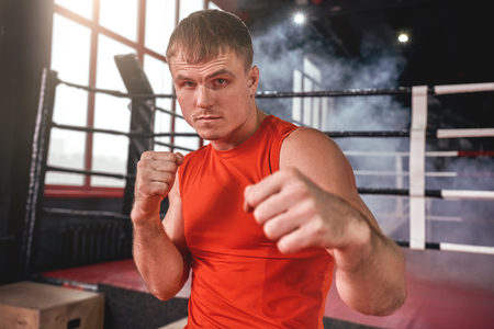 Perfect boxing stance. Close-up of focused muscular boxer in sports clothing looking at camera while...