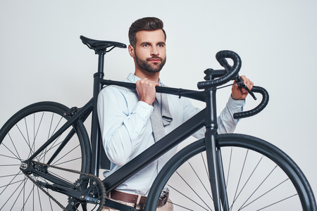 Best transport. Close up photo of good looking man in casual clothes carrying his bicycle. Urban styleの写真素材