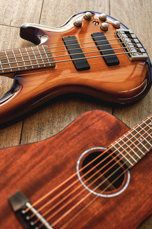 Choosing a guitar...Top view on two perfect polished musical instruments: acoustic and electric guitars are lying on the wooden floor in a music shopの写真素材
