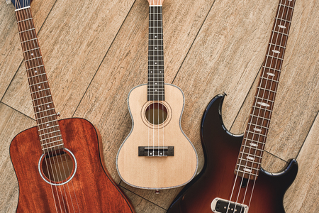 How To Choose Your First Guitar? Top view on three different types of guitars: acoustic, electric and ukulele.の写真素材