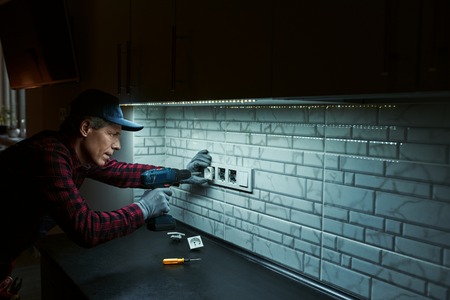 Sockets installation. Close-up of senior handyman setting new socketsの写真素材