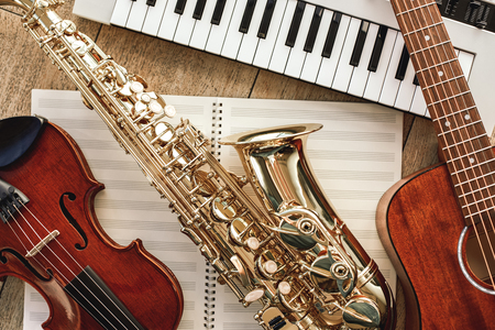 Power of music. Top view of musical instruments set: synthesizer, guitar, saxophone and violin lying...