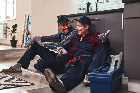 Little rest after hard work. Two handymen sitting on the floorの写真素材