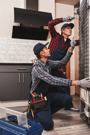 Try to screw this. Two men mechanics checking refrigeratorの写真素材