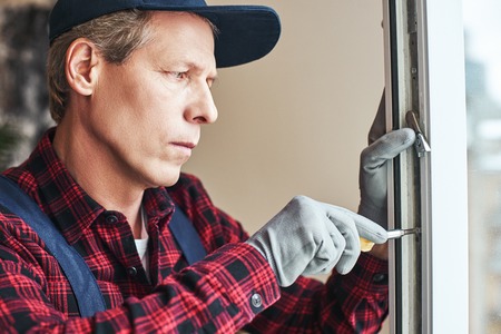 Masters work. Close-up of senior handyman setting new windowsの写真素材