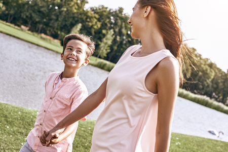 Single parent, Mother and son walking on a grassy field near lakの写真素材