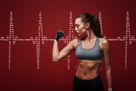 Perfect body. Sportswoman is training with dumbbells standing over red background. Graphic drawing.の写真素材
