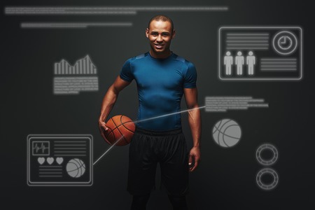 He is a new champion. Handsome sportsman standing over dark background with basketball ball in his hand. Game concept with graphic drawing.の写真素材