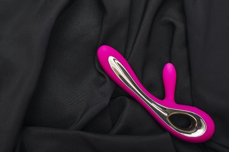 Online shopping. Close up photo of purple silicone G-spot vibrator for her on a black silk fabric.の写真素材