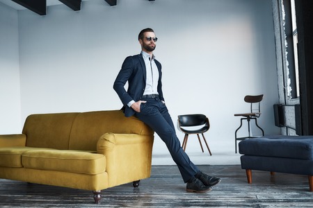 Young stylish businessman leader indoors at office wearing sunglasses looking aside thoughtfulの写真素材
