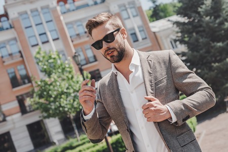 Live each day as if your life had just begun. Portrait of brown-haired man wearing sunglasses and looking away in the city streets.の写真素材