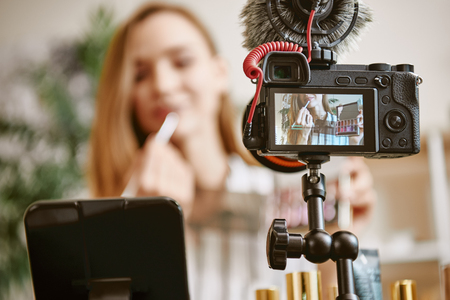 Lips. Close up photo of digital camera with young blogger trying a new lipstick color while online broadcasting in social mediaの写真素材