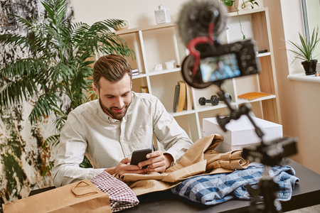Chatting with subscribers. Male fashion blogger answering on questions after online streaming for his blogの写真素材