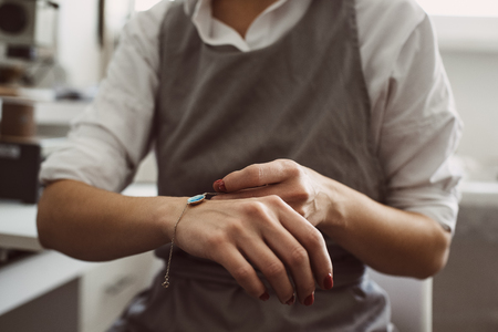 Perfect present. Portrait of female jeweler wearing silver bracelet while working at her jewellery...