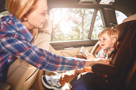 Boy sitting in a car in safety chair. Family road tripの写真素材