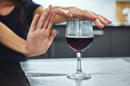 A small step toward recovery is giant progress. Addicted woman refuses to drink a glass of red wine....