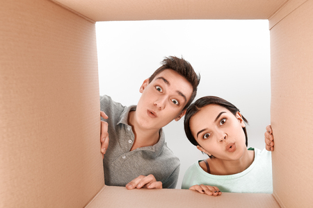 Surpised teens opening a carton box and looking inside, desired purchase conceptの写真素材