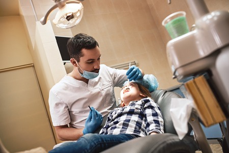The home of radiant smiles. Kid at the dental office. Dentist examining little girls teeth in clinic.の写真素材