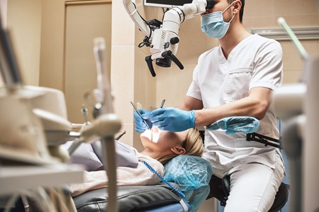Dentistry with a personal touch. Male dentist look at the patient using professional dental...