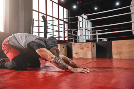 Warm up before training. Young muscular athlete in sports clothing warming up before training in boxing gymの写真素材