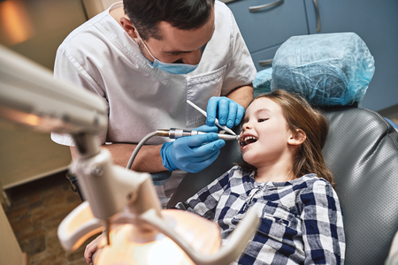 A lifetime of care for you. Male dentist treats child in a dental office. Dentist, child, dental hygieneの写真素材
