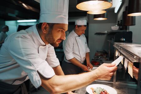 Chef cook checking the order at the restaurant kitchenの写真素材