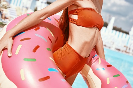 Beautiful body. Built by you. Cropped image of sexy woman wearing red bikini and holding inflatable...