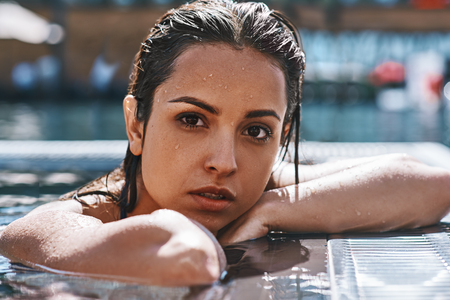 Pure beauty. Portrait of attractive sexy young woman in swimwear looking at camera while standing in swimming pool outdoors.の写真素材