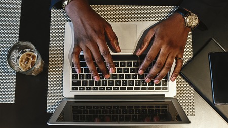 Top view of mans hands typing on a keyboard of the laptop.