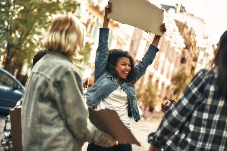 Feeling happy. Cheerful young afro american woman holding blank sign board over her head and...