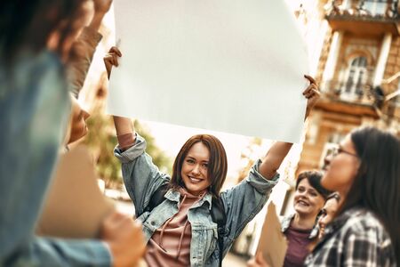 Women power. Happy young woman holding blank sign board over her head and smiling while standing on...