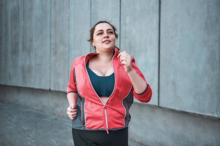 I want to lose weight Young attractive plus size woman in sporty clothes running outdoors in the morningの写真素材