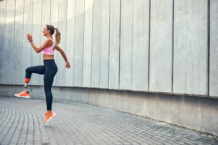 No limits Active disabled woman with leg prosthesis in sports clothing jumping while her morning...