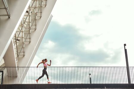 Go Full-length of young disabled woman with leg prosthesis in sports clothing is running on the...