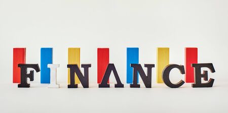 Finance word created with alphabet letters standing in front of multi-colored wooden blocksの写真素材