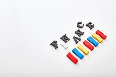 Finance word created with cubes alphabet letters near multi-colored wooden blocks lying diagonallyの写真素材