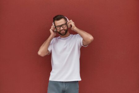 Enjoying my favourite song. Portrait of handsome and cheerful man in eyeglasses wearing headphones...