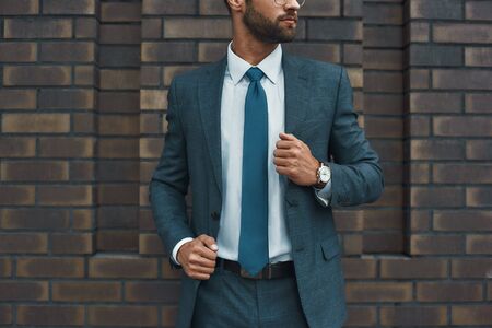 Cropped photo of a businessman in full suit standing against brick wallの写真素材