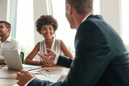 Multicultural team. Young and beautiful afro american woman discussing something with colleagues and...