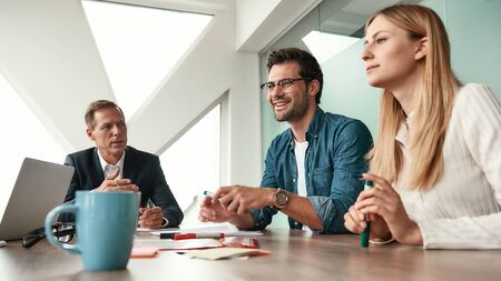 We have great results! Business team discussing something and smiling while sitting in the modern...