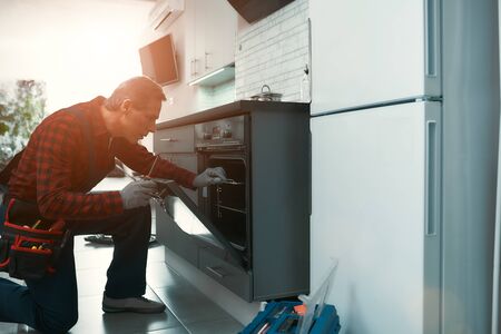 Quality work. Man solves household problems. Side viewの写真素材