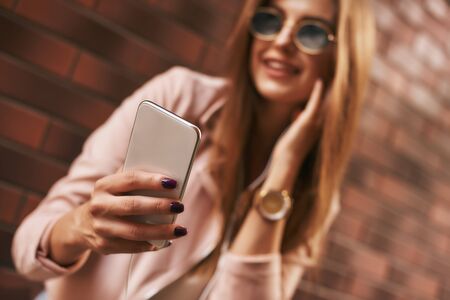 Taking pictures. Beautiful stylishly dressed girl posing over brick backgroundの写真素材